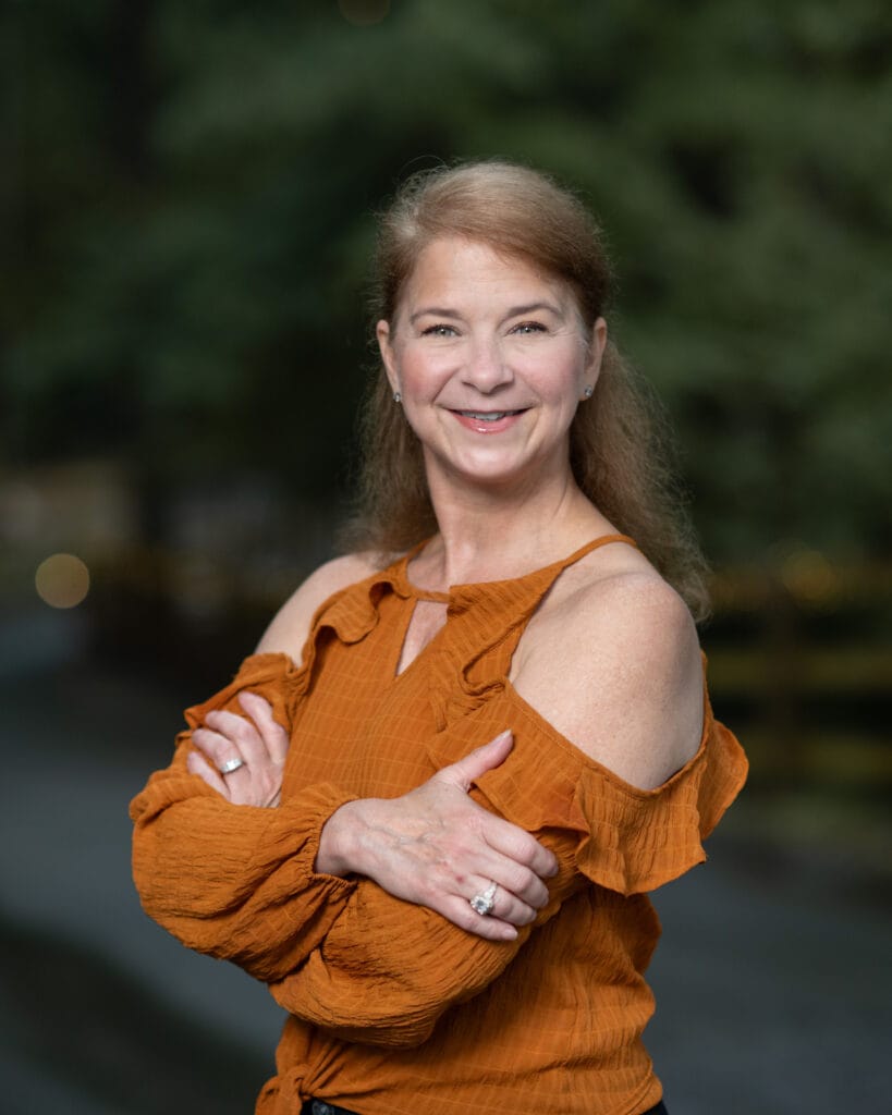 Kirstie Spadie Portrait in orange sweater.